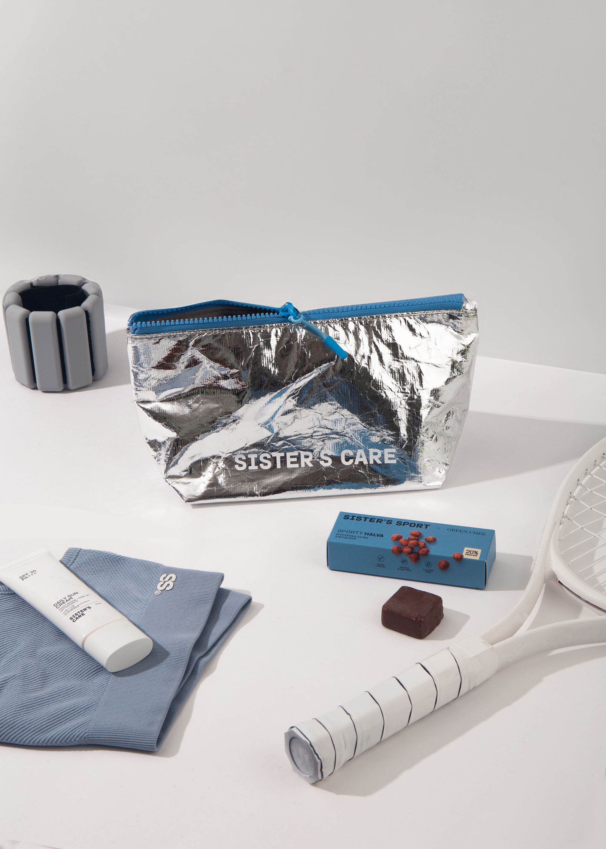 Sister's Aroma cosmetic bag in silver with blue accents, surrounded by fitness and beauty items.