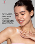 Woman applying cream to her shoulder with text about microbiome protection on a gray background