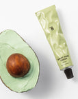 Sister's Aroma Smart Hand Cream in green tube next to halved avocado, showcasing hydrating skincare.