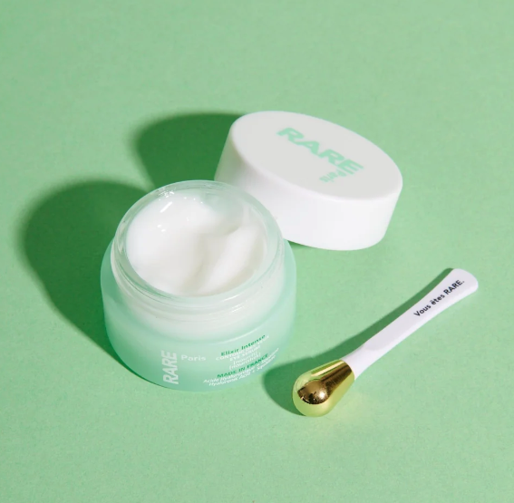 Rare Paris Elixir Intense Eye Serum in mint jar with applicator, promoting hydration and skin elasticity.