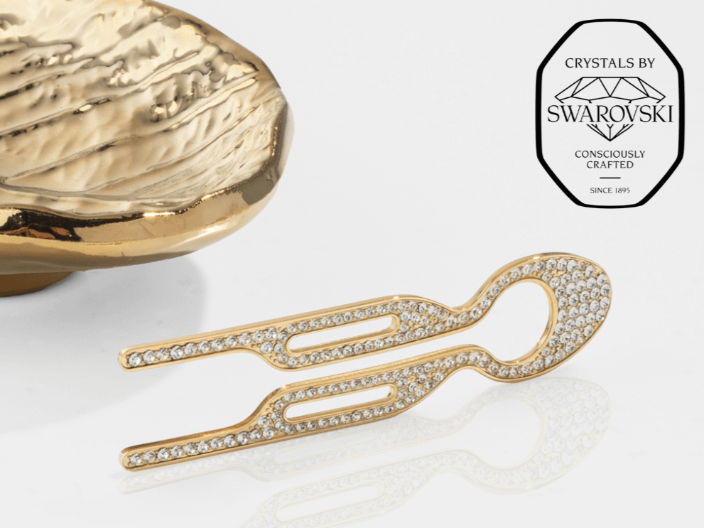 Fiona Franchimon Nº1 HAIRPIN Steel with Swarovski® Crystals | Yellow Gold Finish showcased next to a decorative piece.