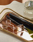 RevitaLash Signature Eyelash Curler Kleštičky na řasy alongside defining liner and cosmetics on a stylish tray.
